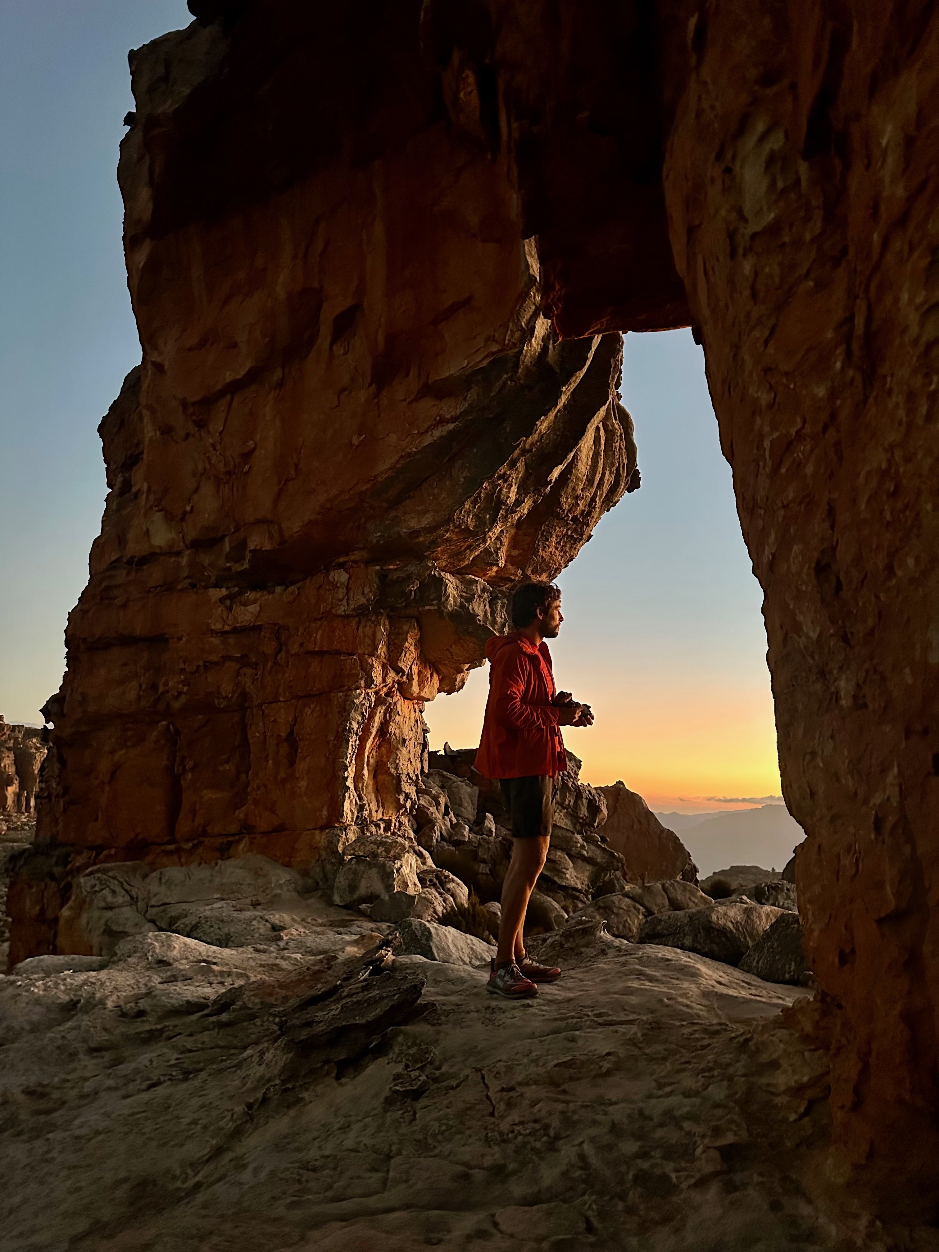 Shawn standing beneath a rock arch at sunset