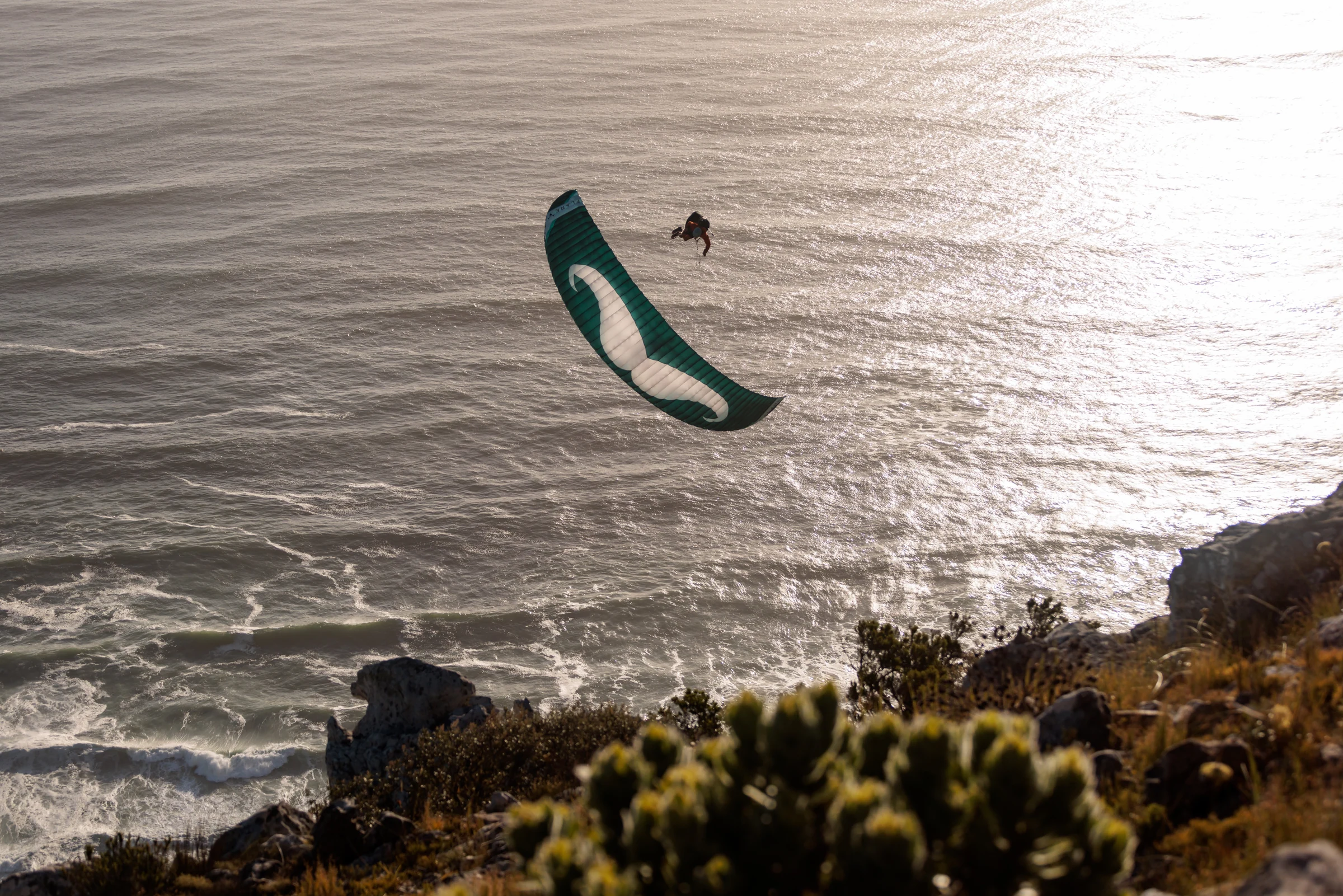 Shawn paragliding above the ocean and rugged coastline